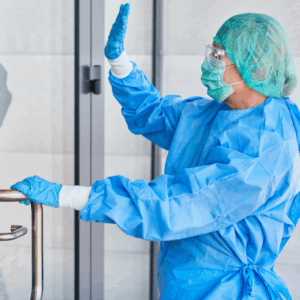 man wearing personal protective equipment waves through the glass door