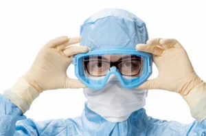 lab worker wearing cleanroom protective equipment, adjusting his cleanroom safety goggles